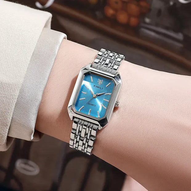 Montre femme avec cadran carré bleu et bracelet en acier, élégante et minimaliste.