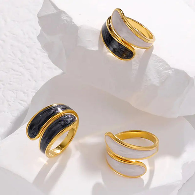 Trois bagues ajustables en titane avec finitions dorées et couleurs contrastantes sur un fond en pierre