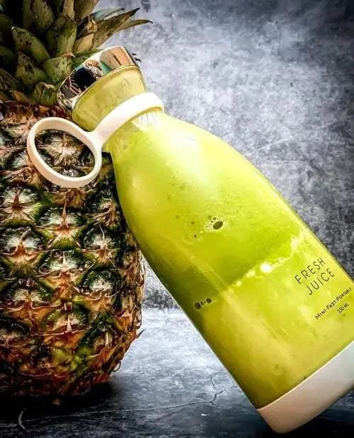 Beautysky portable blender for smoothies next to a fresh pineapple, showcasing vibrant green juice