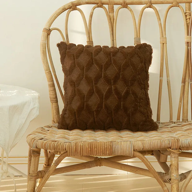 Housse coussin fourrure marron texturée sur un canapé en rotin pour une décoration intérieure élégante
