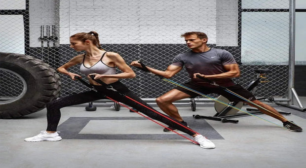 Couple faisant de l'exercice avec un kit bandes résistance entraînement dans une salle de sport moderne