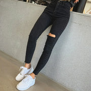 Jean skinny noir femme avec déchirures et coupe ajustée, porté avec des baskets blanches
