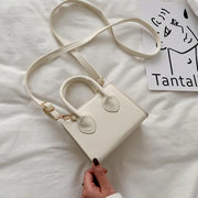 petit sac à main cuir blanc élégant avec bandoulière réglable sur un fond blanc