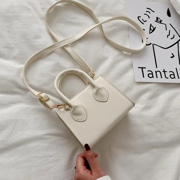 petit sac à main cuir blanc élégant avec bandoulière réglable sur un fond blanc