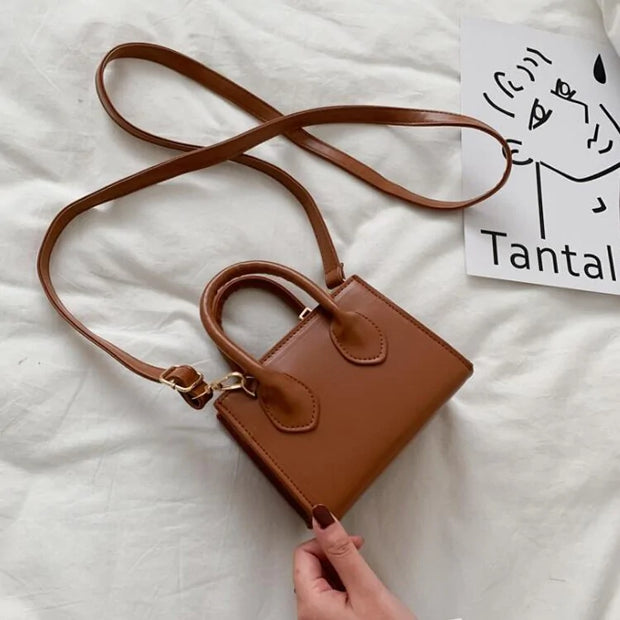 Elegant petit sac à main en cuir marron avec bandoulière réglable, design chic et compact.