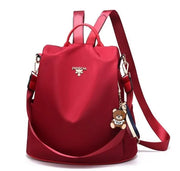 Waterproof Oxford backpack for women in vibrant red with adjustable straps and teddy bear charm.