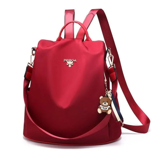 Waterproof Oxford backpack for women in vibrant red with adjustable straps and teddy bear charm.