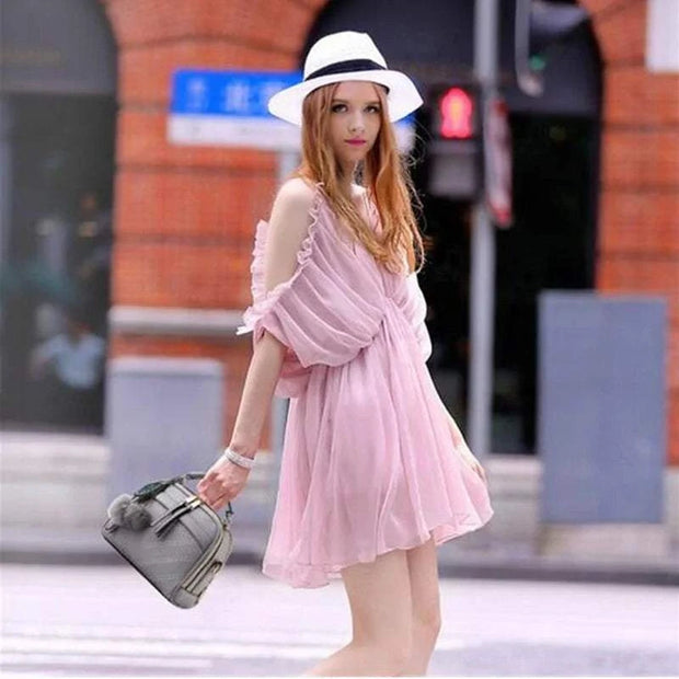 Femme portant une robe rose avec un sac à main cuir tendance et un chapeau sur une rue urbaine