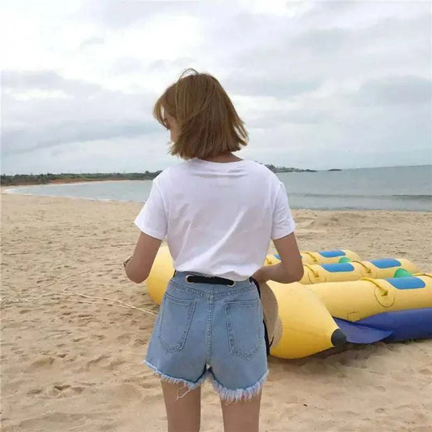 High-waisted denim shorts with belt on beach.